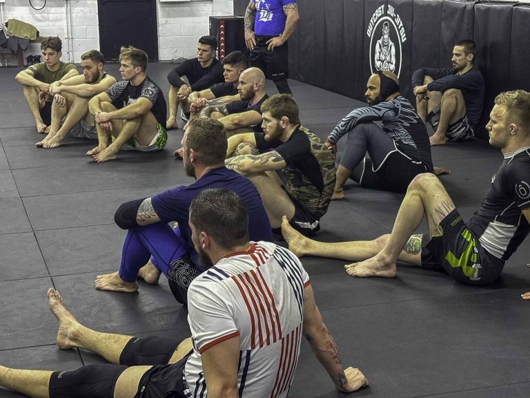 Jiu-jitsu students listening to their coach during martial arts classes at Upgraded Industries